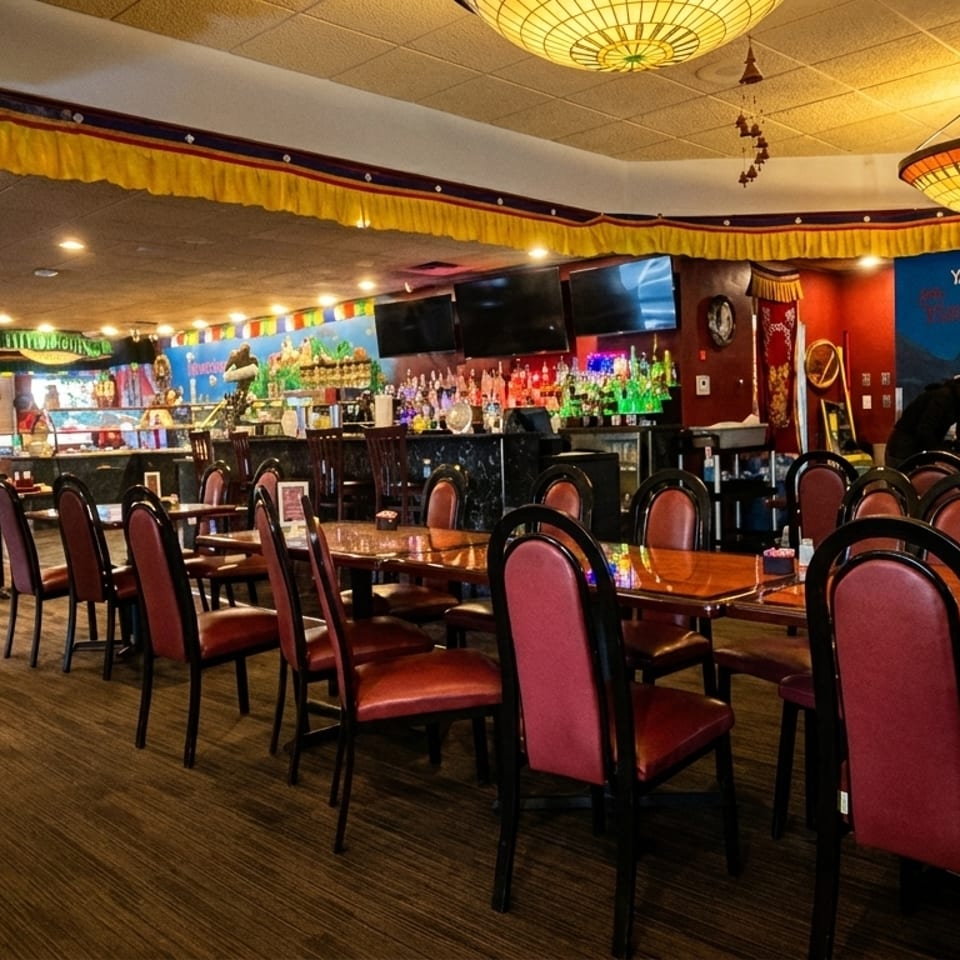 Interior of a restaurant with red chairs, wooden tables, a bar, and a mural of mountains and a yeti.